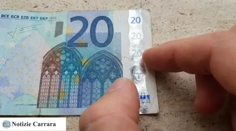 Dettaglio di una banconota da 20 euro con un dito che indica la striscia olografica di sicurezza