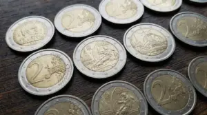 Monete da 2 euro, incluse emissioni commemorative, disposte su un tavolo di legno