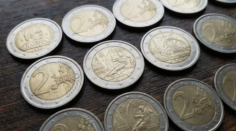 Monete da 2 euro, incluse emissioni commemorative, disposte su un tavolo di legno