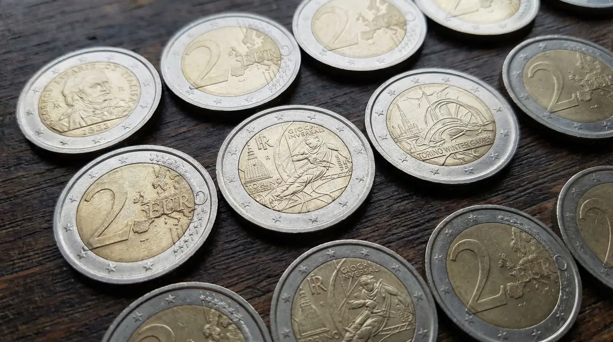 Monete da 2 euro, incluse emissioni commemorative, disposte su un tavolo di legno