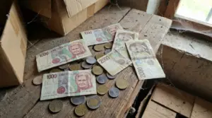 Banconote e monete in lire italiane trovate in soffitta su un tavolo di legno polveroso, vicino a scatole di cartone