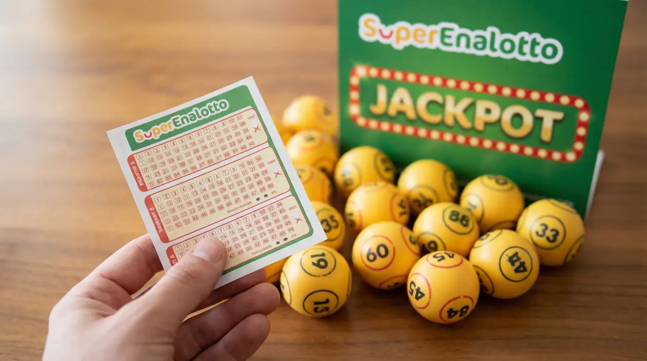 Mano che tiene una schedina del SuperEnalotto vicino a palline numerate e a un cartello del jackpot