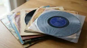 Pila di dischi in vinile con copertine vintage su un tavolo, con un vinile in primo piano nella sua custodia